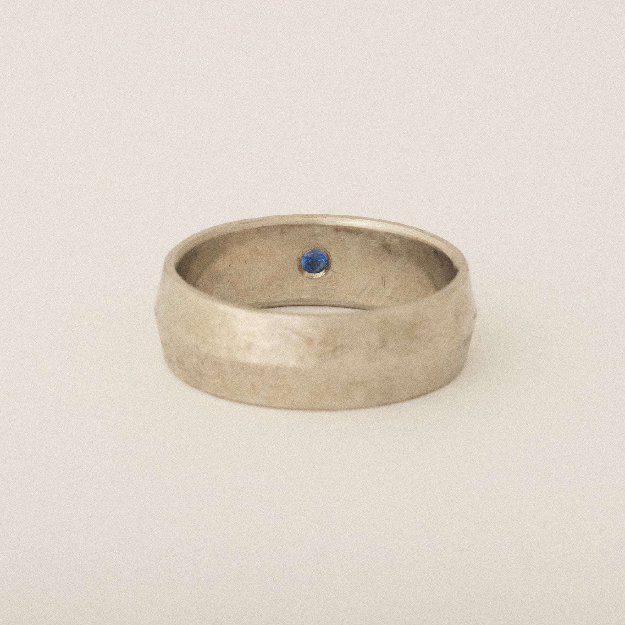 Subtle Knife's Edge Platinum Distressed Finish with Interior Blue Sapphire Flush Set Wedding Band